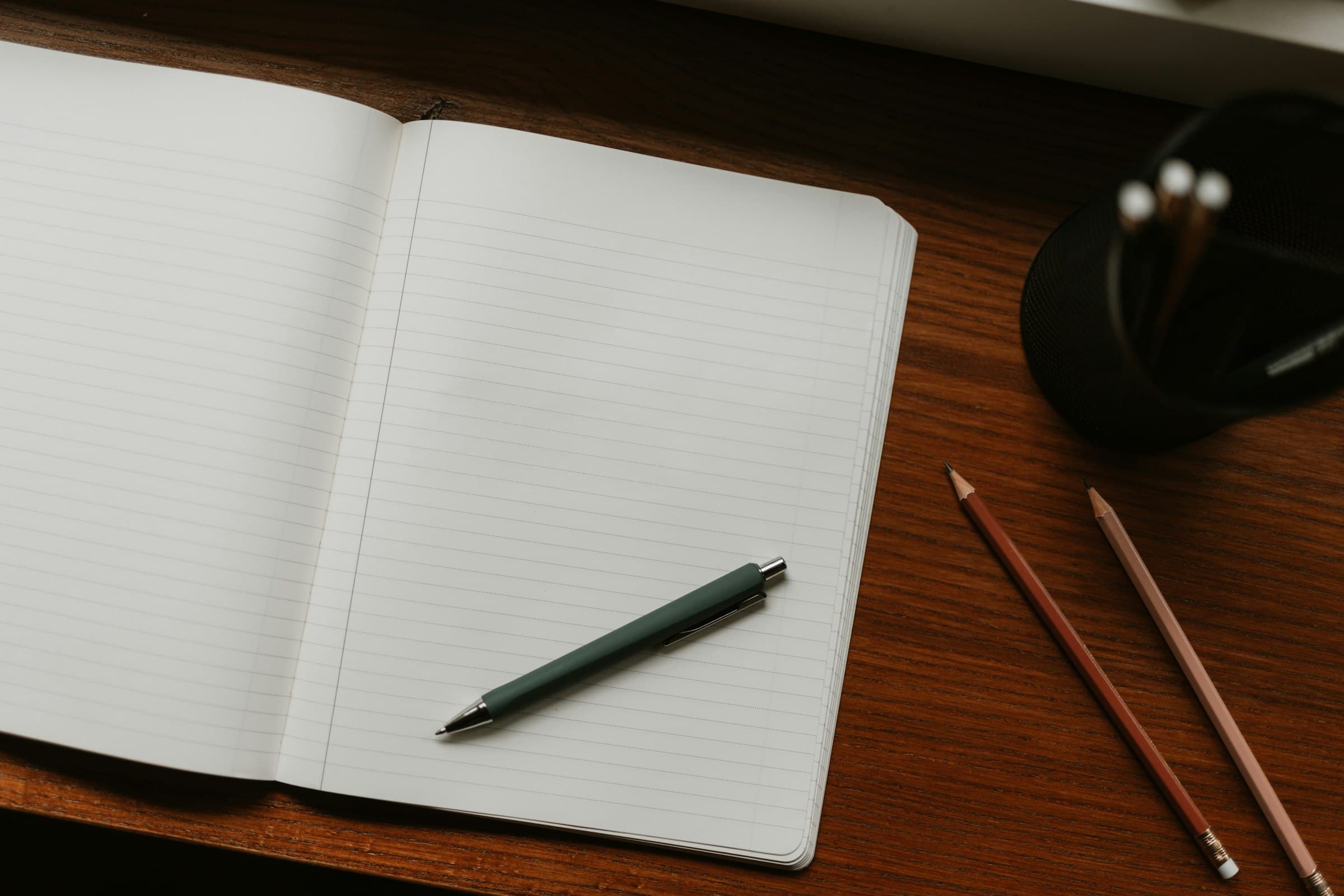 An open notebook with a pen and pencils, ready for writing