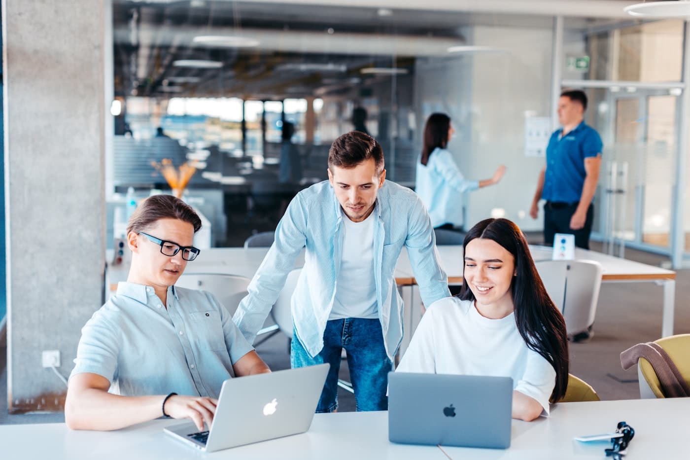 A small team of developers collaborating together around laptops in a bright office