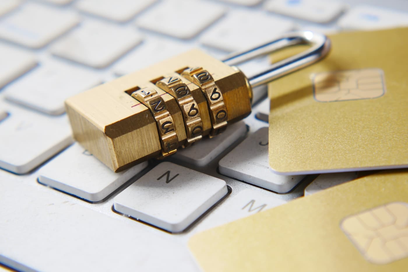 A padlock and credit cards resting on a laptop keyboard, representing secure authentication and subscription payments