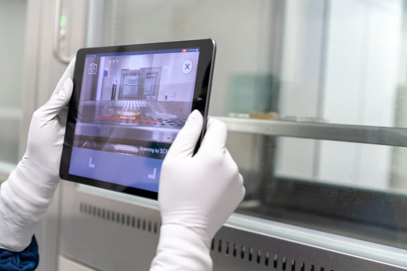 Gloved hands using a tablet to run an inspection scan in a technical facility